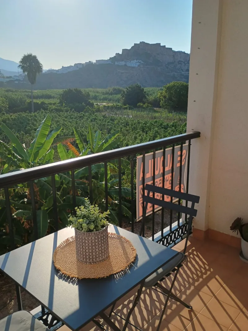 Terraza con mesa y sillas, con la vega y el castillo de Salobreña al fondo