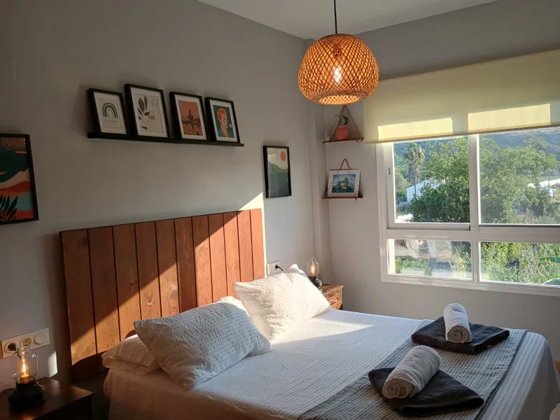 Dormitorio con cabecero de madera y luz de la tarde