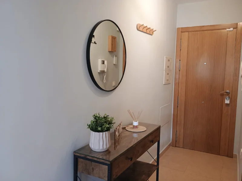 Detalle del recibidor: espejo, perchero y puerta de entrada