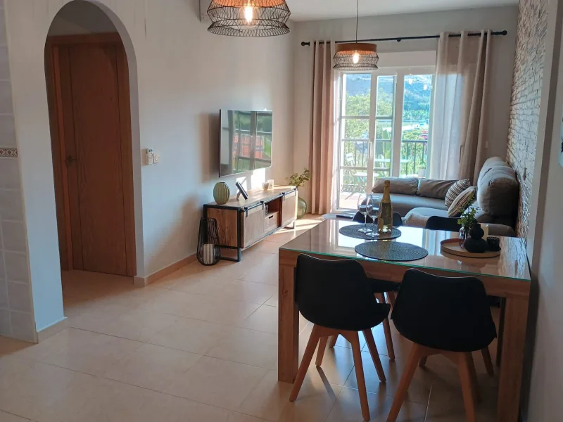 Salón con mesa de comedor, sofá y salida a la terraza