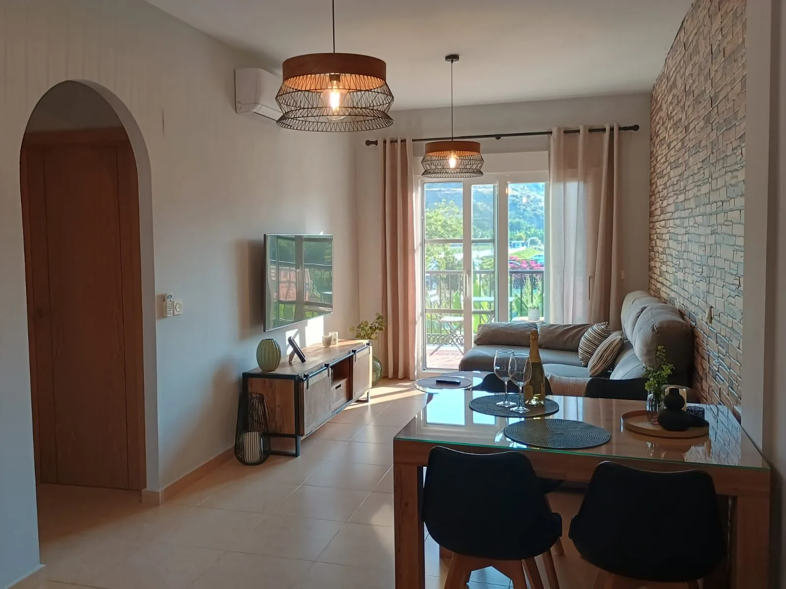 Salón comedor con balcón, pared de piedra vista y arco de entrada